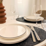 Gedeckter Esstisch mit Tellern und Besteck auf Unterleger
